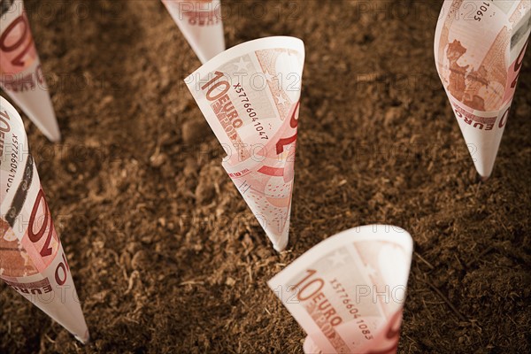 Rolled up ten euro notes stuck in ground. Photo : Mike Kemp