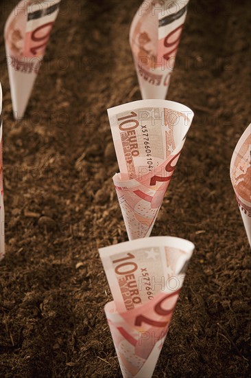Rolled up ten euro notes stuck in ground. Photo : Mike Kemp