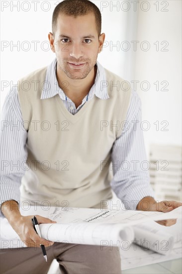 South Africa, Portrait of young man holding blueprints. Photo : momentimages