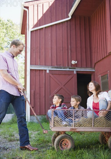 USA, New York, Flanders, Father pulling mother and two boys (4-5, 8-9) on trolley. Photo : Jamie Grill Photography