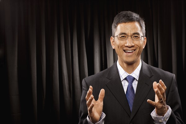 USA, Utah, Provo, Portrait of businessman having speech in front of black curtain. Photo : FBP