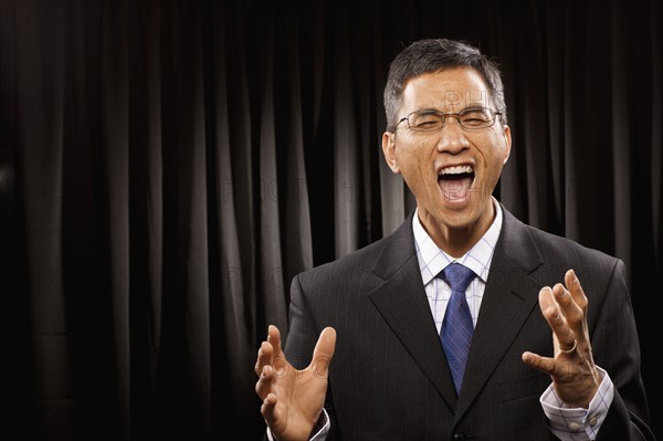 USA, Utah, Provo, Portrait of businessman having speech in front of black curtain. Photo : FBP