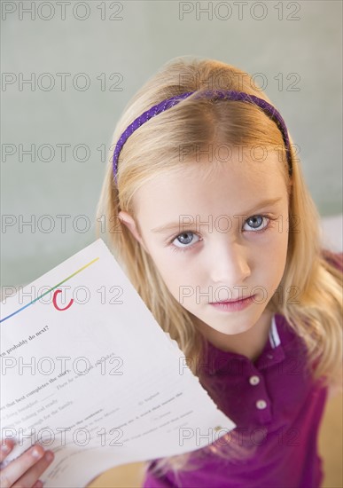 USA, New Jersey, Jersey City, Sad schoolgirl (8-9) showing test results with C-grade. Photo : Jamie Grill Photography