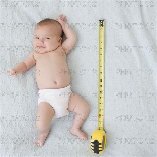 USA, New Jersey, Jersey City, baby girl laying (2-5 months) laying next to measuring tape. Photo : Jamie Grill Photography