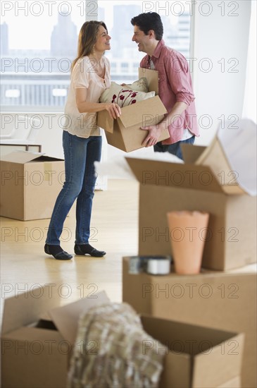 USA, New Jersey, Jersey City, Couple carrying box in new home.