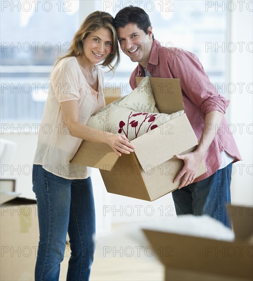 USA, New Jersey, Jersey City, Portrait of couple carrying box in new home.