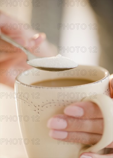 USA, New Jersey, Jersey City, Close-up view of human hand putting sugar into cup of coffee. Photo : Jamie Grill Photography