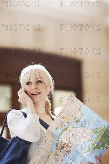 USA, Seattle, Young woman talking via phone and holding map. Photo : Take A Pix Media