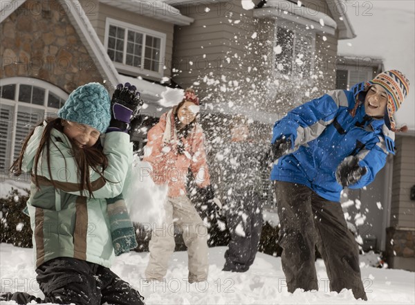 USA, Utah, Provo, Boys (10-11, 12-13) and girls (10-11, 16-17) having snow ball fight in front of house. Photo : FBP