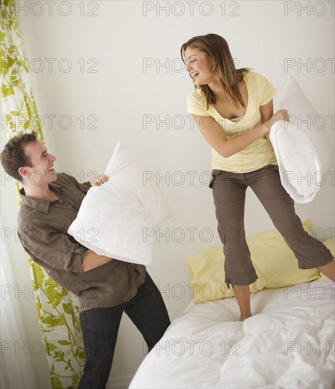 USA, New Jersey, Jersey City, Portrait of young couple fighting with pillow.