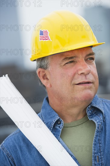 USA, New Jersey, Jersey City, Construction worker holding blueprints on construction site.