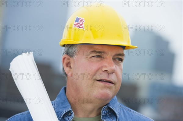 USA, New Jersey, Jersey City, Construction worker holding blueprints on construction site.