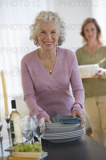 USA, New Jersey, Jersey City, Portrait of senior woman holding plates, with daughter in background.