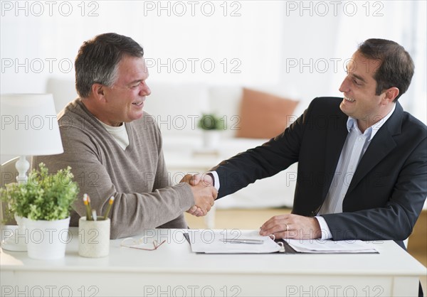 USA, New Jersey, Jersey City, Man shaking hands with financial advisor in home.