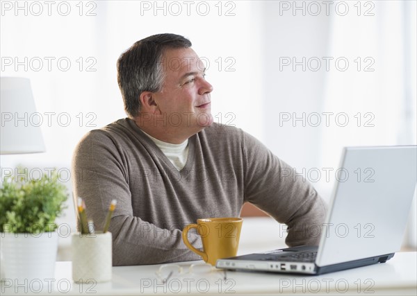 USA, New Jersey, Jersey City, Pensive man using laptop in living room.