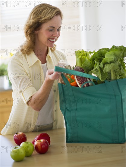 USA, New Jersey, Jersey City, Woman with grocery bag in kitchen.