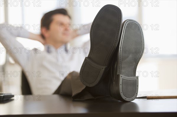 USA, New Jersey, Jersey City, Businessman with feet up on desk.