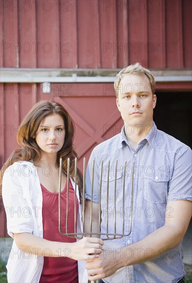 USA, New York, Flanders, Portrait of mid adult couple with pitchfork. Photo : Jamie Grill Photography