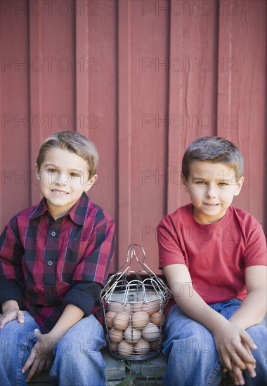 USA, New York, Flanders, Brothers (4-5, 8-9) posing with basket of eggs. Photo : Jamie Grill Photography