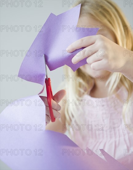 USA, New Jersey, Jersey City, Girl (8-9) cutting star shape in paper. Photo : Jamie Grill Photography