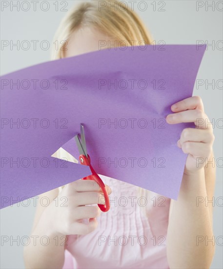 USA, New Jersey, Jersey City, Girl (8-9) cutting star shape in paper. Photo : Jamie Grill Photography