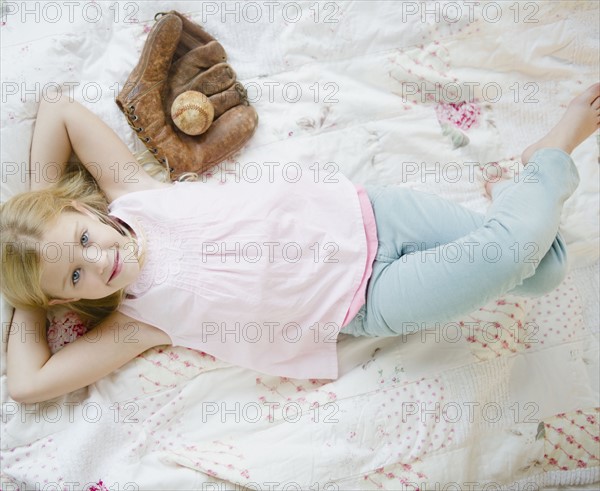 USA, New Jersey, Jersey City, Girl (8-9) laying beside baseball glove and ball. Photo : Jamie Grill Photography