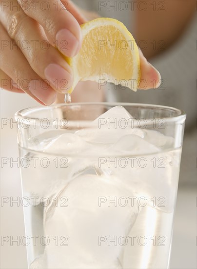 USA, New Jersey, Jersey City, Close-up view of woman's hand squeezing lemon into refreshness drink. Photo : Jamie Grill Photography