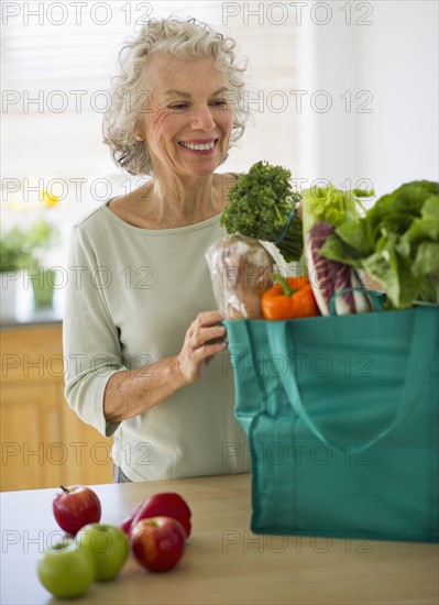 USA, New Jersey, Jersey City, Senior woman with grocery bag in kitchen.
