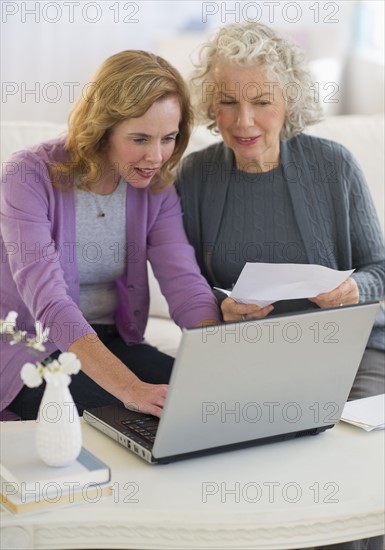 USA, New Jersey, Jersey City, Mother and daughter using laptop in living room.