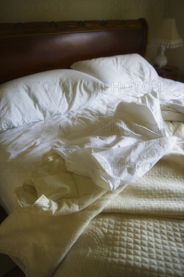 Unmade bed with white duvet.