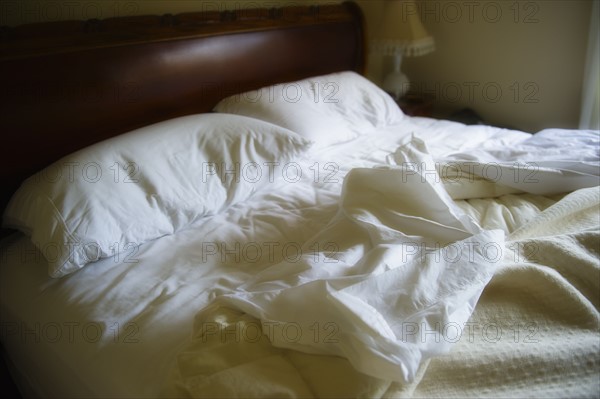 Unmade bed with white duvet.
