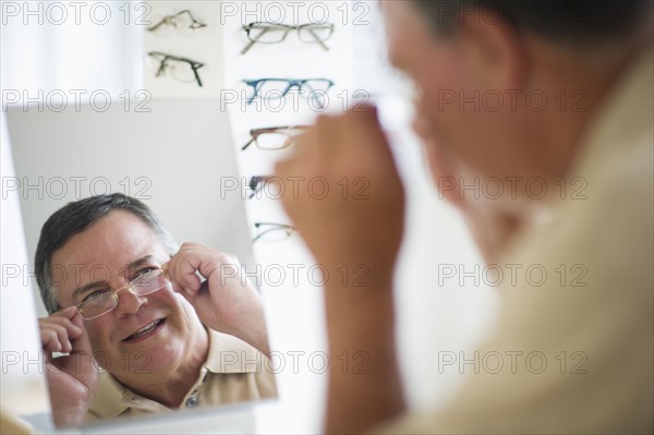 USA, New Jersey, Jersey City, Man trying on glasses in shop mirror.