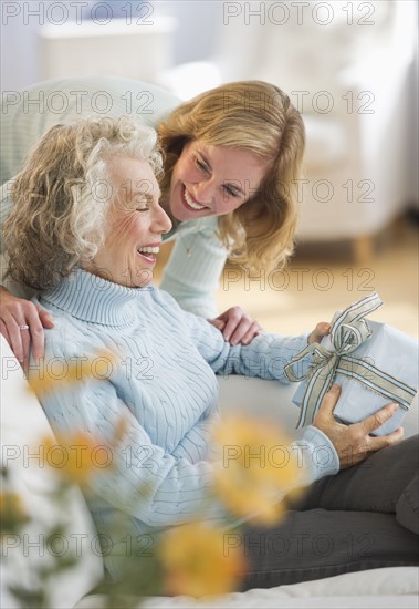 USA, New Jersey, Jersey City, Senior woman receiving present from daughter on sofa.
