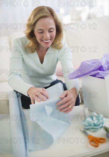 USA, New Jersey, Jersey City, Woman wrapping gifts in living room.