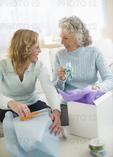 USA, New Jersey, Jersey City, Senior mother and daughter wrapping gifts in living room.