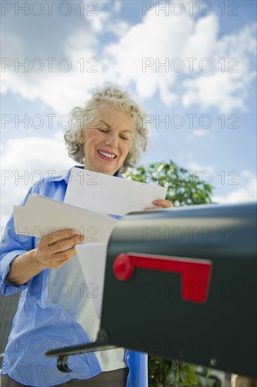 USA, New Jersey, Jersey City, Senior woman checking mail at mailbox.