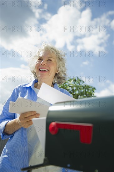USA, New Jersey, Jersey City, Senior woman checking mail at mailbox.