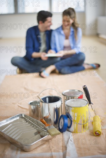 USA, New Jersey, Jersey City, Couple sitting near painting equipment in new home .