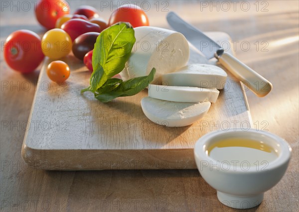 Mozarella and tomatoes on chopping board.