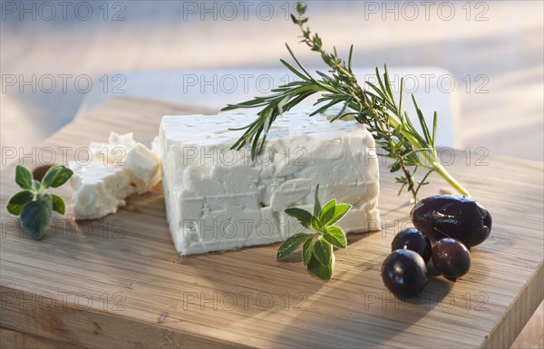 Cheese with herbs on chopping board.