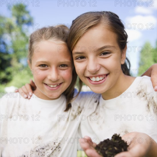 USA, New York, Two girls (10-11, 10-11) holding soil wearing dirty t-shirts. Photo : Jamie Grill Photography