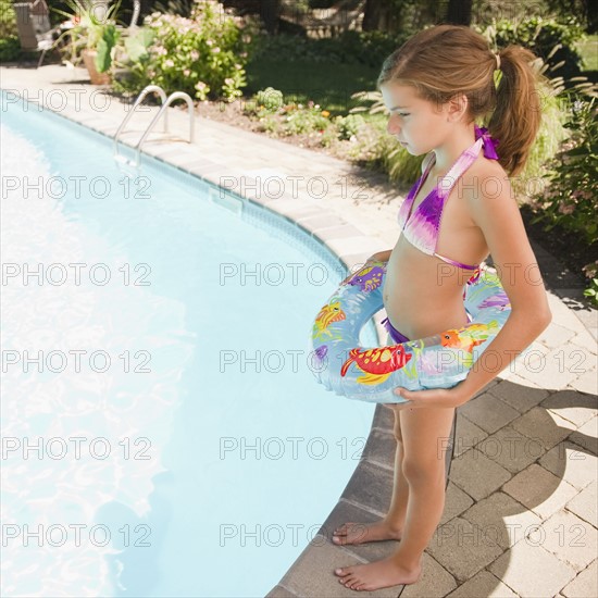 USA, New York, Girl (10-11) standing next to swimming pool. Photo : Jamie Grill Photography