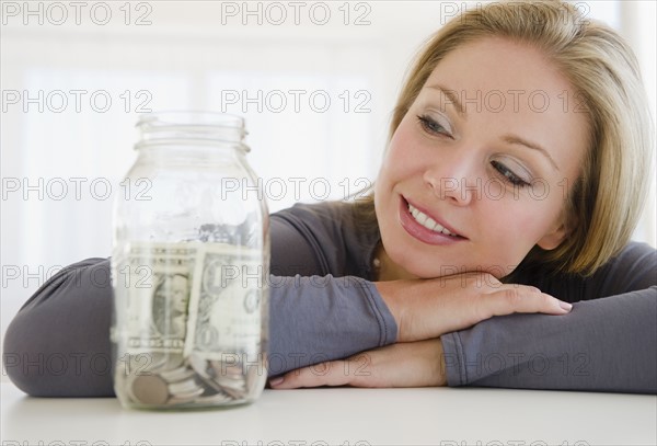 USA, New Jersey, Jersey City, Young attractive woman watching improvised jar - piggybank. Photo : Jamie Grill Photography