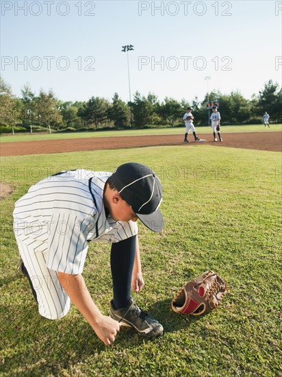 USA, California, boy (10-11) from little league baseball team tying lace.