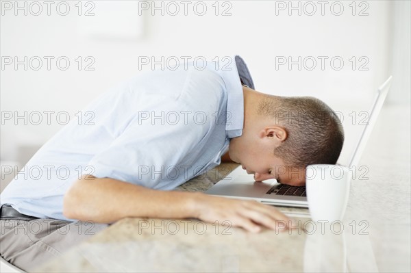 South Africa, Man with forehead on his laptop. Photo : momentimages