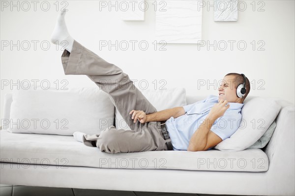 South Africa, Young man listening music and pretending to play guitar. Photo : momentimages