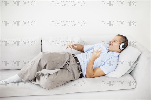 South Africa, Young man listening music and pretending to play guitar. Photo : momentimages