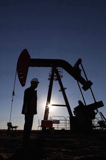 Silhouette of oil worker by pump jack on rig. Photo : Dan Bannister