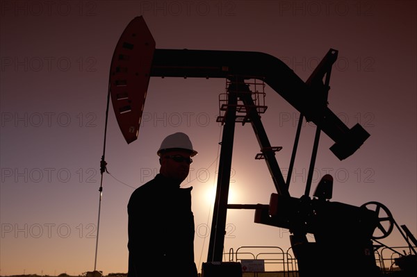 Silhouette of oil worker by pump jack on rig. Photo : Dan Bannister