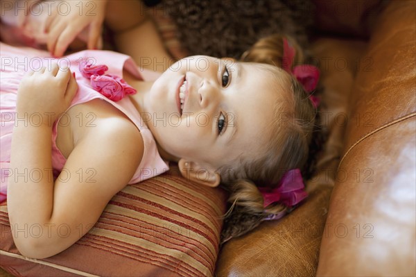 Happy girl lying on sofa, high angle view. Photo : FBP